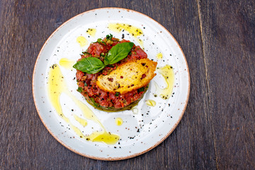 Tuna tartare with vegetables lies on plate.