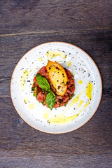 Tuna tartare with vegetables lies on plate.