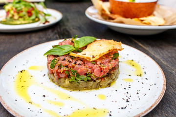 Tuna tartare with vegetables lies on plate.