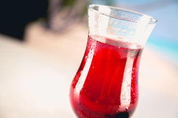 Colorful red cold drink on a beach, summer background