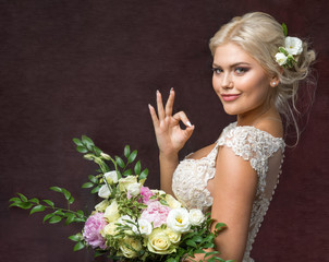 Naklejka premium beautiful bride with bouquet of flowers and a gesture OK