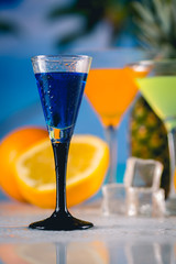 Blue exotic drink on the beach with palms in background