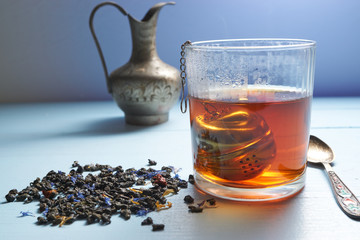 closeup glass of hot tea with tea strainer and tea leaves