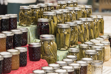 Farmers market booth selling pickled vegetables and canned fruit, selectively focused on the front...