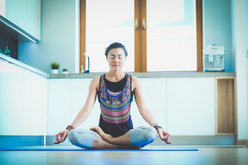 Young woman doing yoga at home in the lotus position. Yoga. Woman. Lifestyle