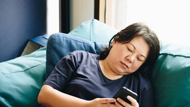Asia women 40s holding smartphone thinking on sofa