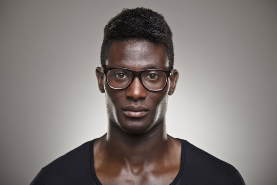 African young real man with glasses over grey background