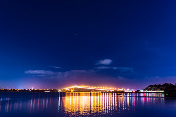 cars in motion on a lighted bridge over the sea with a starry sky, boats in Auckland, New Zealand