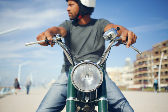 Young tough looking man waiting while sitting on his old timer moped