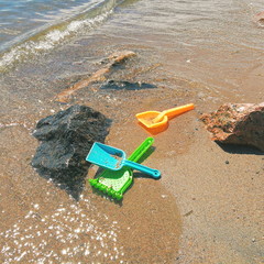 Colored children beach toys on sand and sea 