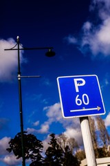 Sign: P 60, Parking 60 minutes, blue and white. Street light and sky in background