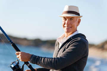 Senior man fishing at sea side