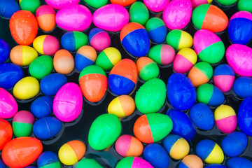 Colorful plastic eggs floating on water background