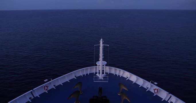 An evening establishing shot of a large cruise ship's bow as it travels on the open ocean.  	