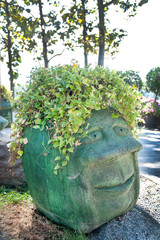 Stone human head with vine in the park