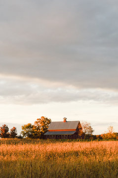 Red Barn Or Stable In A Field Of Dry Grass In Autumn