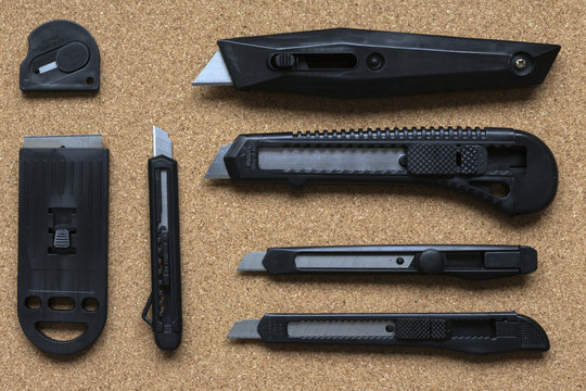 A selection of office knives on a cork background