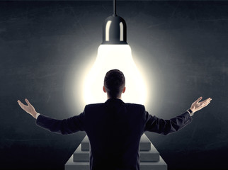Man standing on a step in front of a huge light bulb