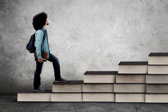 African student climbs stair shaped books