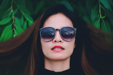 Hipster woman face wears black sunglasses on nature background.