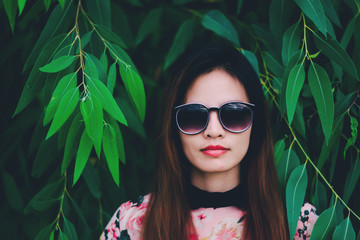 Hipster woman face wears black sunglasses on nature background.