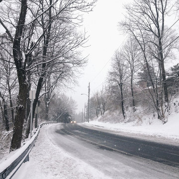 An oncoming car on a snowy road in winter.