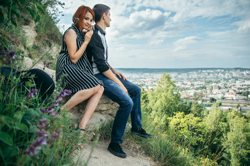 Fototapeta premium couple sitis on the hill with ponaramic view