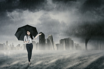Businesswoman walking with umbrella in rain