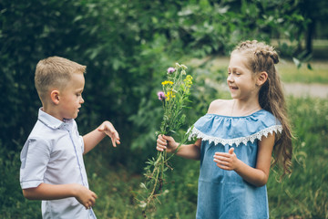 the little boy gives the girl a bunch of flowers