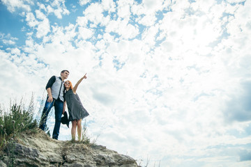 young man with woman stands on the hill and points straight ahead