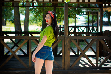 Pretty brunette woman in pin up style have fun and enjoying life on vacation. Stylish inspire vintage lady on a beach near wooden alcove, water and sand