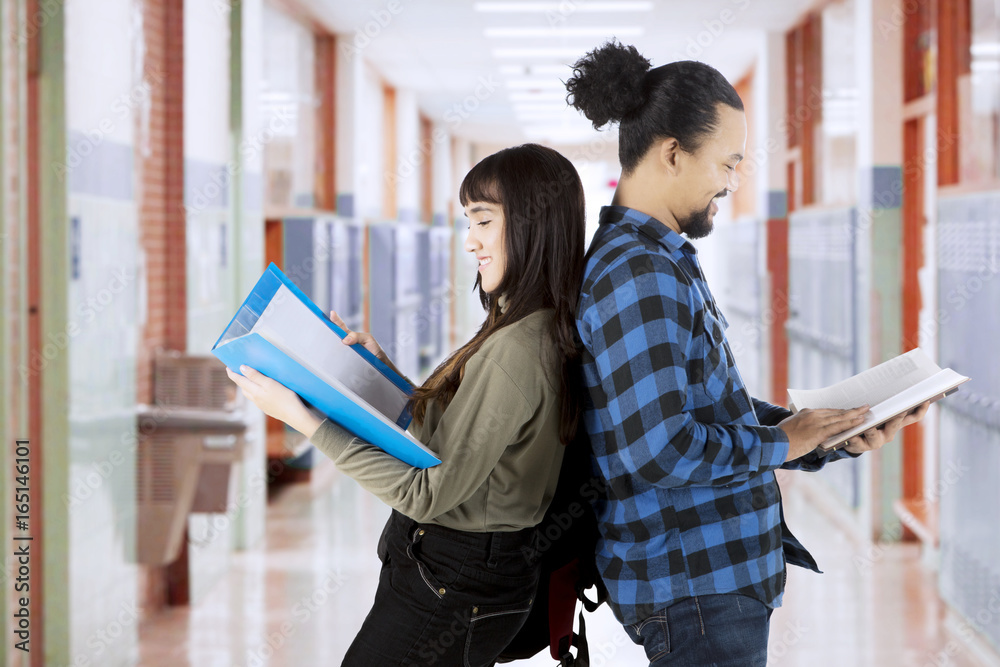 Wall mural students read book in school corridor