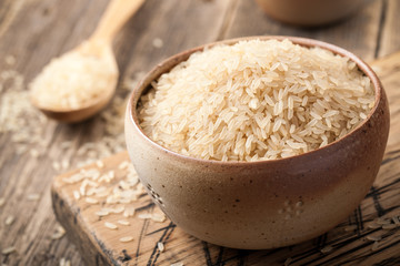 Uncooked parboiled rice in a bowl on wooden table