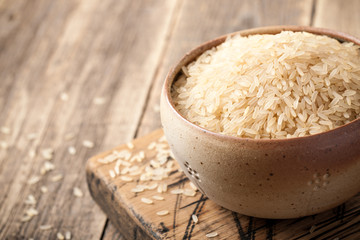 Uncooked parboiled rice in a bowl on wooden table