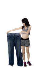 Woman with slim body holds big jeans