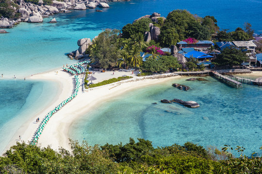 Tropical island getaway with a sand strip beach and blue sea water