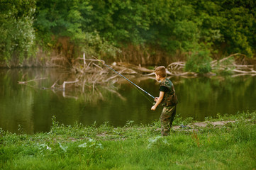 Naklejka na ściany i meble Boy catches fish in the river.The concept of tourism and leisure