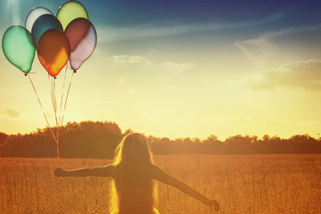 Fototapeta premium Silhouette of girl with balloons in the sunset background.