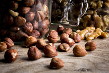 Hazelnuts and walnuts in jars on a chopping board