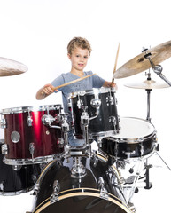 Fototapeta premium young caucasian boy plays drums in studio against white background