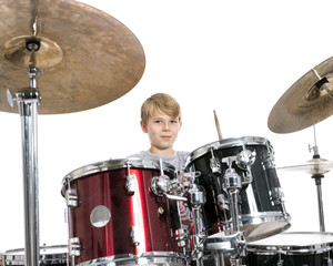 young teen boy plays the drums in studio against white background