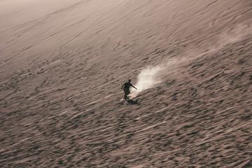 Silhouette of man doing sandboard on desert dunes