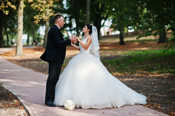Amazing young gorgeous newly married couple taking a walk in the park on their wedding day.