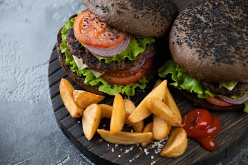 Close-up of two beef burgers with black sesame bun, selective focus, horizontal shot