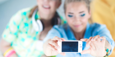 Two girls taking pictures on the phone at home
