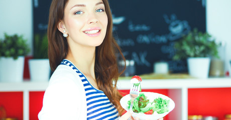 Young woman eating salad and holding a mixed