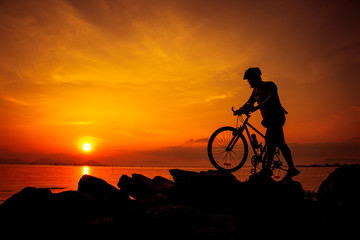 Fototapeta na wymiar Silhouette of bicyclist enjoying the view at seaside. Outdoors.