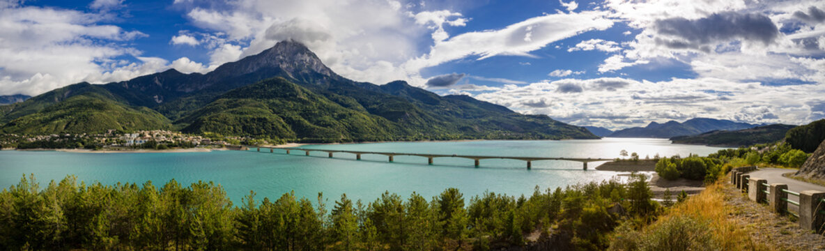 Panoramic view of Serre-Poncon Lake with Savines-le-Lac and its bridge with the Grand Morgon mountain peak in summer. Hautes-Alpes, Durance Valley, PACA Region, Southern French Alps, France