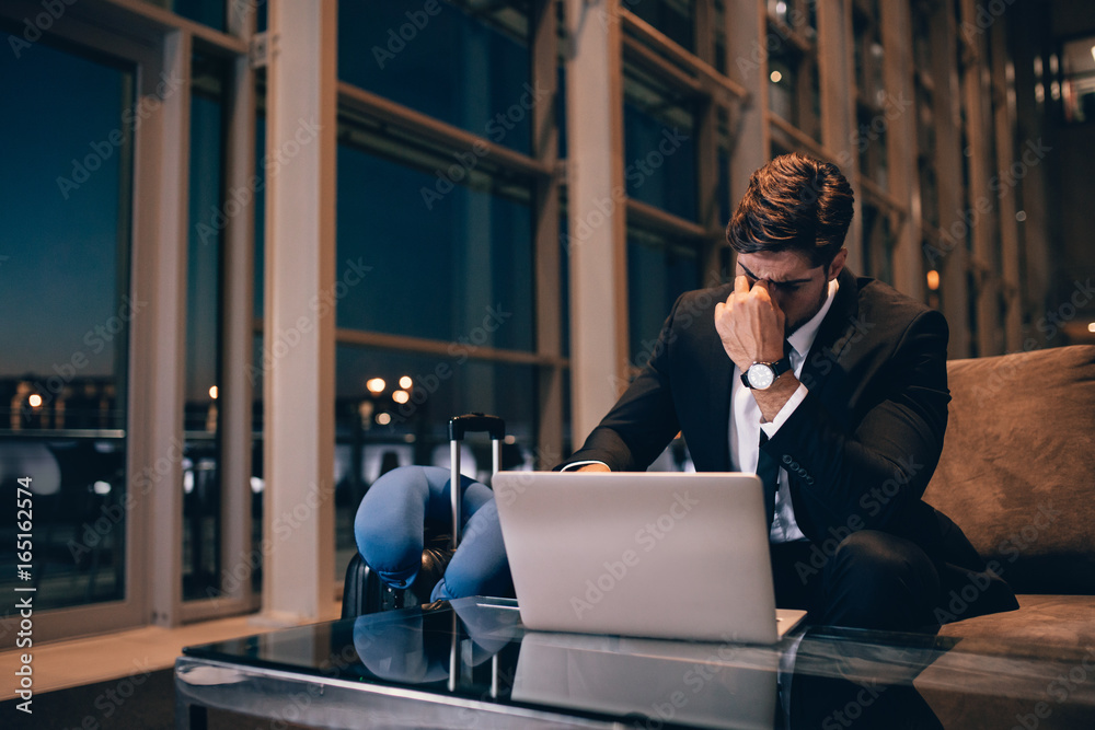 Poster Tired businessman waiting for delayed flight in airport lounge