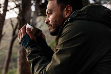 Male hiker taking rest and having coffee outdoors